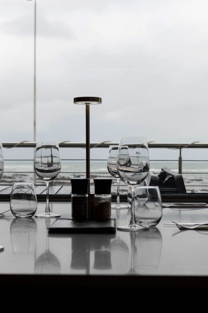 A table set with wine glasses beside the window overlooking the sea at Prime Wagyu, Strand