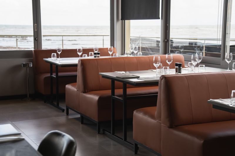 Brown booth seating and tables beside the beachfront windows